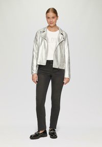 Zilverkleurige metalen motorjack, witte T-shirt met de tekst "LOVE", zwarte skinny jeans en zwarte instappers. Glad materiaal en slim fit ontwerp.