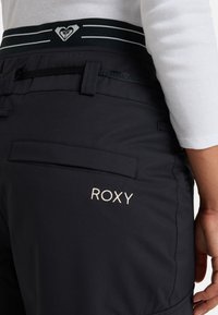 Zwarte sneeuwbroek met een verstelbare tailleband en een contrasterende gestreepte band, Roxy-logo in geborduurd beige, verstevigde zakken.