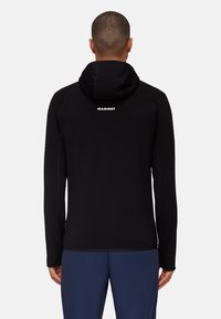 Black hoodie with a fitted design, made of soft fabric. Features a hood and contrasting seams. "Mammut" logo on the upper back.