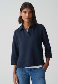 Pull bleu marine avec un col, des manches trois-quarts et un ourlet droit. Fabriqué en tissu lisse et léger.