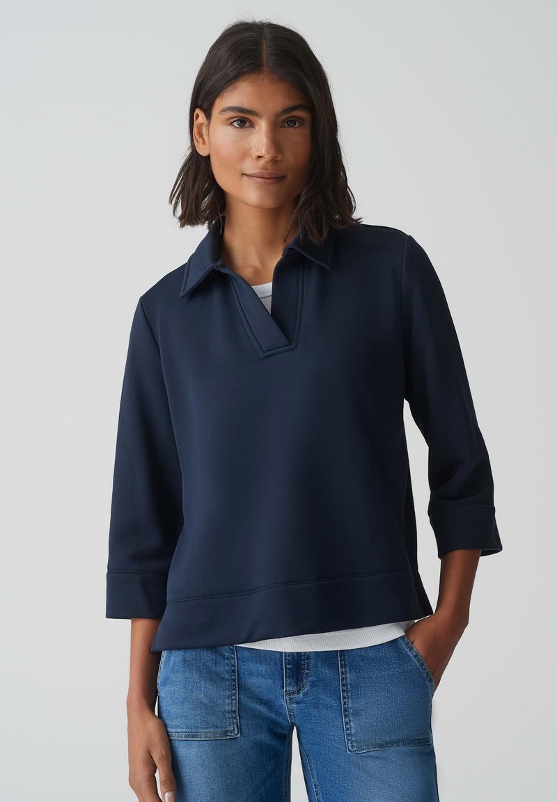 Pull bleu marine avec un col, des manches trois-quarts et un ourlet droit. Fabriqué en tissu lisse et léger.