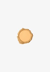 Maquillage poudre compacte beige clair avec de la poudre libre dispersée autour de ses bords sur un fond blanc.
