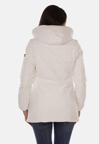 Giacca bianca con cappuccio, dalla silhouette aderente, texture liscia e dettagli di cucitura visibili. La vista posteriore mostra un design semplice e linee pulite.