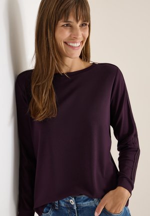 Paarse lange mouwen shirt met een ronde halslijn, voorzien van subtiele textuuraccenten op de mouwen en een relaxte pasvorm, gecombineerd met blauwe jeans.