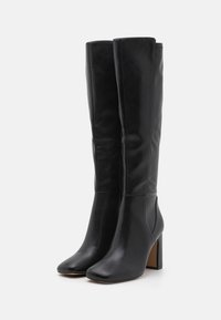 Knee-high black leather boots with a square toe and a chunky heel. Smooth texture with minimal detailing, providing a sleek appearance.