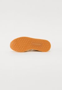 Narancssárga gumiból készült sneaker talp, gyémánt mintázattal, dombornyomott "adidas" logóval és texturált felülettel a tapadás érdekében.