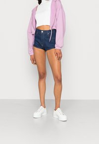 Sudadera de cremallera rosa claro, top corto blanco de canalé, pantalones cortos de mezclilla azul oscuro y zapatillas de plataforma blancas. Texturas suaves, ajuste relajado.