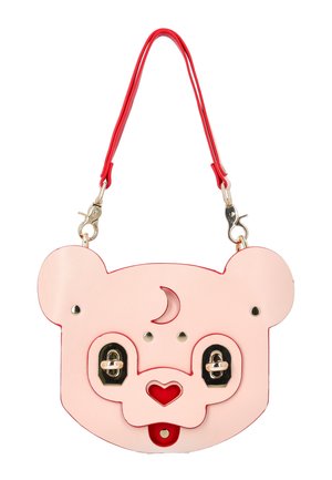 Różowa torebka w kształcie misia z czerwonym nosem w kształcie serca, detalem półksiężyca na czole, złotymi zapięciami jako oczami oraz odpinanym czerwonym paskiem.