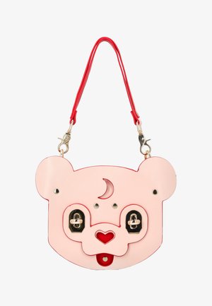 Różowa torebka w kształcie misia z czerwonym nosem w kształcie serca, detalem półksiężyca na czole, złotymi zapięciami jako oczami oraz odpinanym czerwonym paskiem.