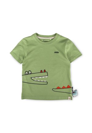Light green short-sleeve kids’ T-shirt with a cartoon crocodile graphic, red details, and a small attached blue plush toy at the hem.