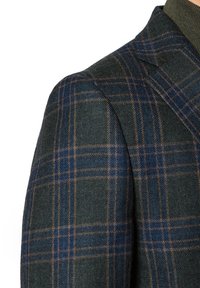 Wełniana marynarka w ciemnozielonym kolorze, z klasycznym wzorem w niebieskie i brązowe kraty. Wyraźnie zarysowane ramiona oraz teksturowany materiał.