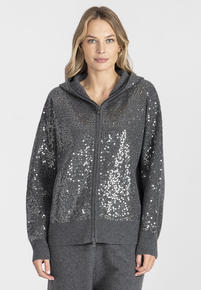 Szara bluza z kapturem zapinana na zamek, wykonana z tkaniny o fakturze, z cekinowym wzorem na przodzie. Posiada kaptur oraz ściągacze na rękawach i u dołu.
