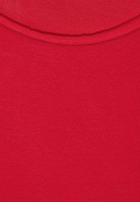 Czerwona tkanina o gładkiej fakturze, podkreślająca jednolity kolor bez wzorów. Materiał wydaje się miękki i lekki.