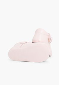 Bota de cuero rosa con punta redondeada, textura suave, suela plana, correa ajustable y acento de botón en el lateral.