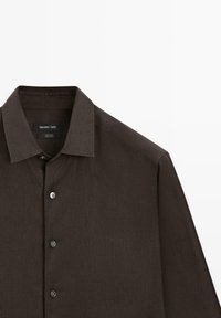Camicia di lino marrone scuro a maniche lunghe con colletto appuntito e quattro bottoni visibili, etichettata Massimo Dutti.