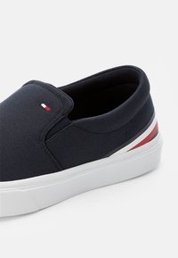 Námornícky plátený klín s bielou gumovou podrážkou. Na patě se nacházejí červené a bílé pruhy a na svršku je malé logo.