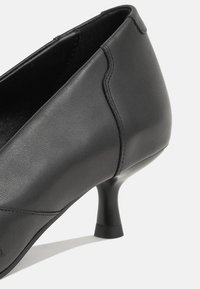 Escarpin femme en cuir noir avec petit talon kitten et coutures visibles sur fond blanc.