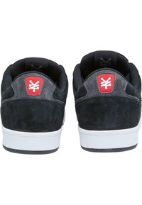 Încălțăminte de skateboard din suede negru, cu o finisare texturată, talpă din cauciuc alb și accente roșii ale logo-ului pe călcâi. Design dual-ton în nuanțe de gri și negru.