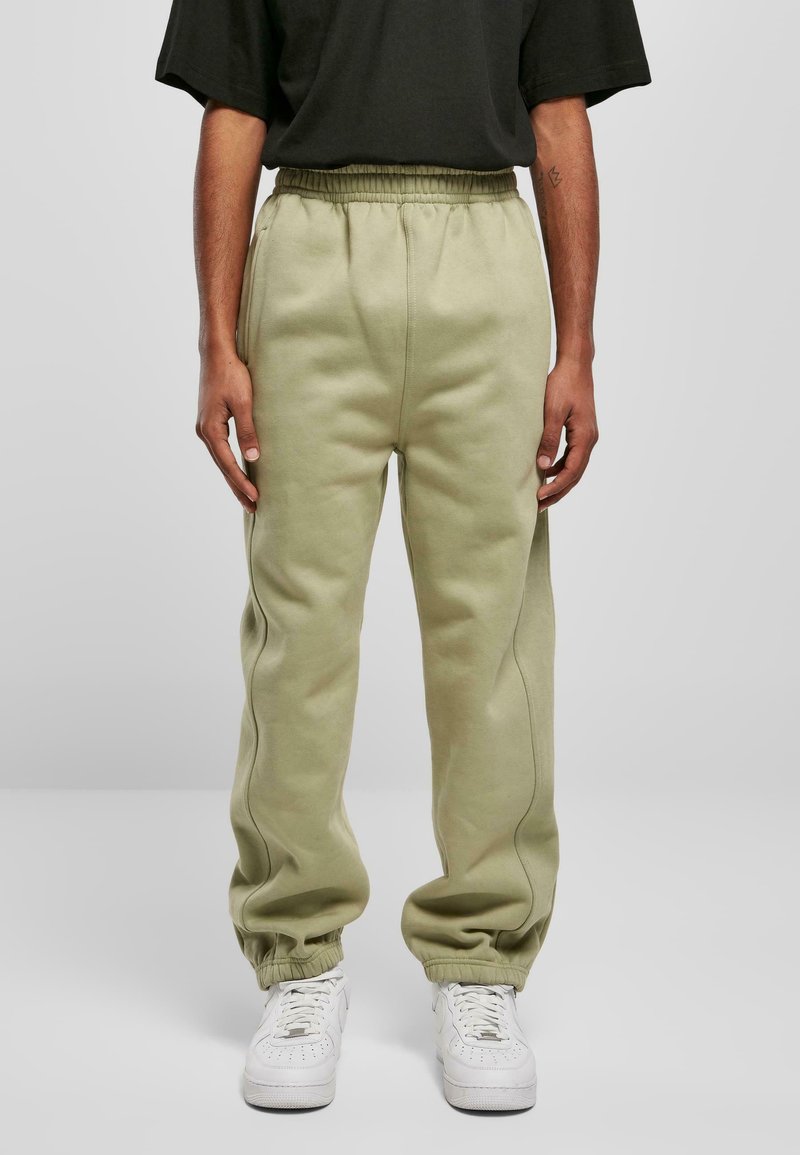 Light green sweatpants with an elastic waistband and cuffs, featuring subtle side stitching details. Paired with white sneakers.