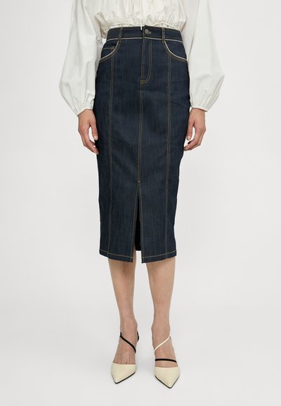 Fustă tip creion din denim de culoare albastru închis, cu cusături galbene, slit frontal, talie înaltă și un design ajustat. Purtați cu tocuri ascuțite de culoare deschisă.