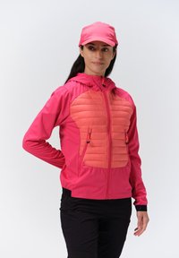 Pink jakke med en quiltet orange panel ved brystet, frontlynlåse og hætte. Blevet parret med en matchende pink cap. Har elastiske manchetter.