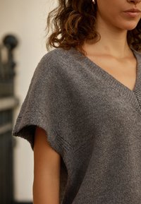 Gray knit sweater with a V-neck and short sleeves, featuring a soft texture and relaxed fit. Simple design with minimal accents.