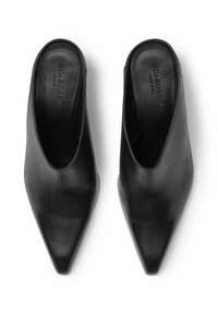 Mules de cuero negro con puntera puntiaguda y parte trasera abierta. Textura suave con un sutil logo en el interior. Diseño clásico y minimalista.