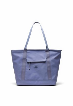 Sac cabas lavande avec longues anses, une poche à rabat sur le devant et le logo "Herschel Supply Company" embossé sous la poche.