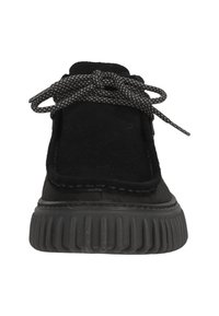 Black suede shoe with a textured surface, round toe, prominent lacing, and a thick rubber sole with ridged detailing.