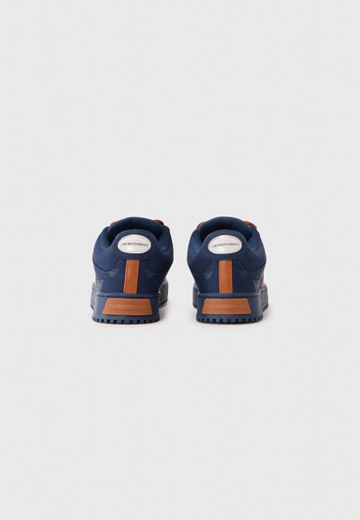 Baskets navy avec une tige texturée, accents en cuir orange et une semelle en caoutchouc avec un motif rainuré ; logo sur le talon et la languette.