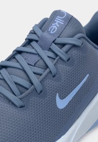 Nike sportcipő világoskék hálós anyagból, tonális fűzőkkel és egy kontrasztos világoskék Swoosh logóval az oldalon.