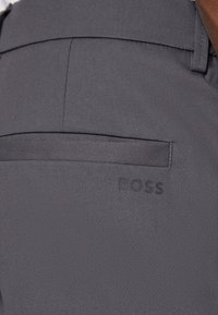 Šedé kalhoty s elegantním designem, hladkou texturou a zadní kapsou s embosovaným logem "BOSS". Odolná tkanina s moderním střihem.