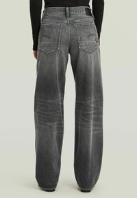 Jeans a gamba larga in denim grigio sbiadito, con un alto punto vita, due tasche posteriori e dettagli di whiskering sottili.