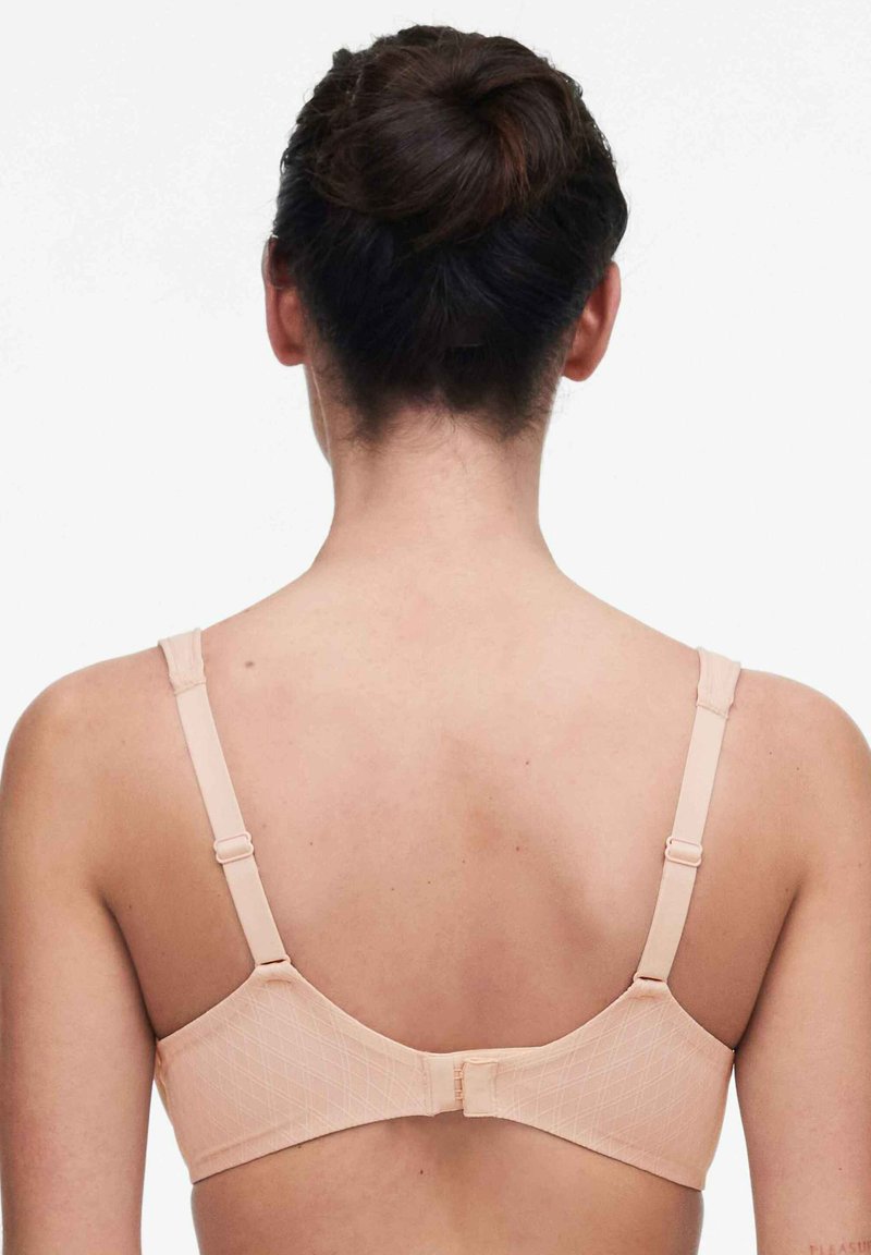 Nuder BH mit einem Diamantmuster, verstellbaren Trägern und einem Haken- und Ösenverschluss hinten. Glatte Textur, minimales Hardware-Detail.