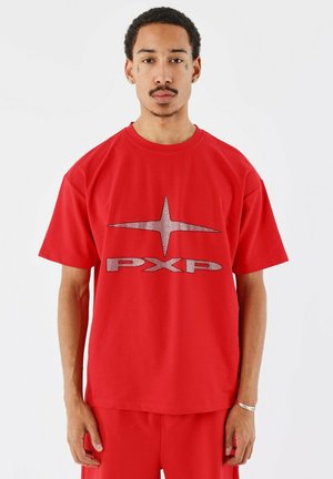 T-shirt en coton rouge avec un grand logo argenté "PXP" et un design d'étoile. Manches courtes et encolure ronde avec une coupe décontractée.
