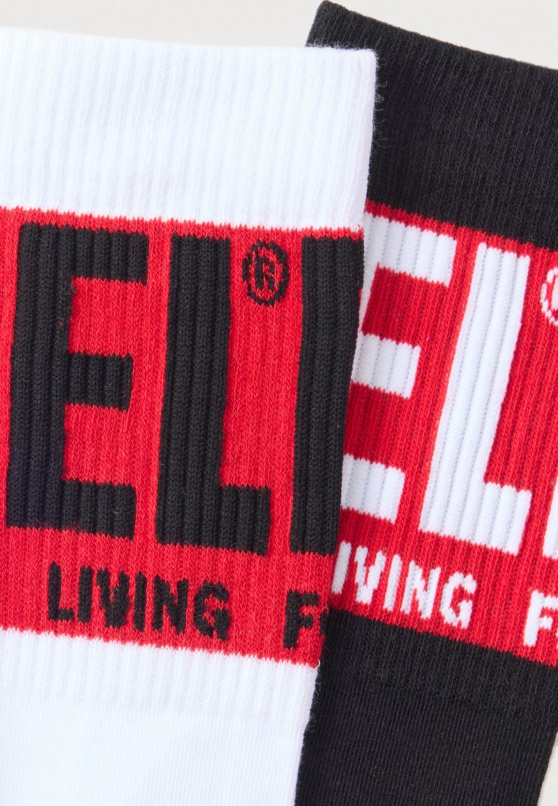 Two pairs of socks in black and white, featuring large red and black text. Ribbed texture with branding visible on each sock.