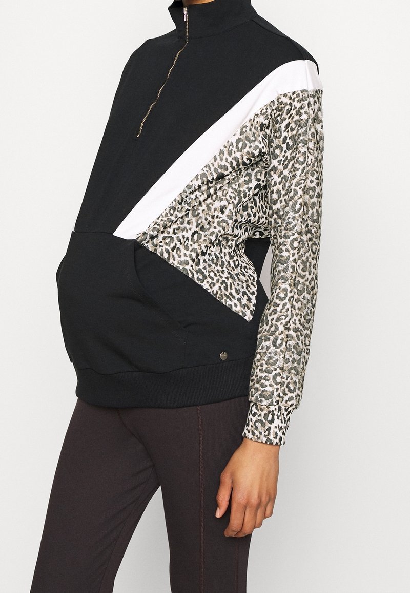 Zwart-witte half-zip sweatshirt met een luipaardprintpatroon op één mouw. Gemaakt van zacht materiaal met een voorkant kangaroozak.