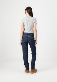 Gray short-sleeve shirt paired with dark blue straight-leg jeans and brown ankle boots, viewed from the back against a plain background.