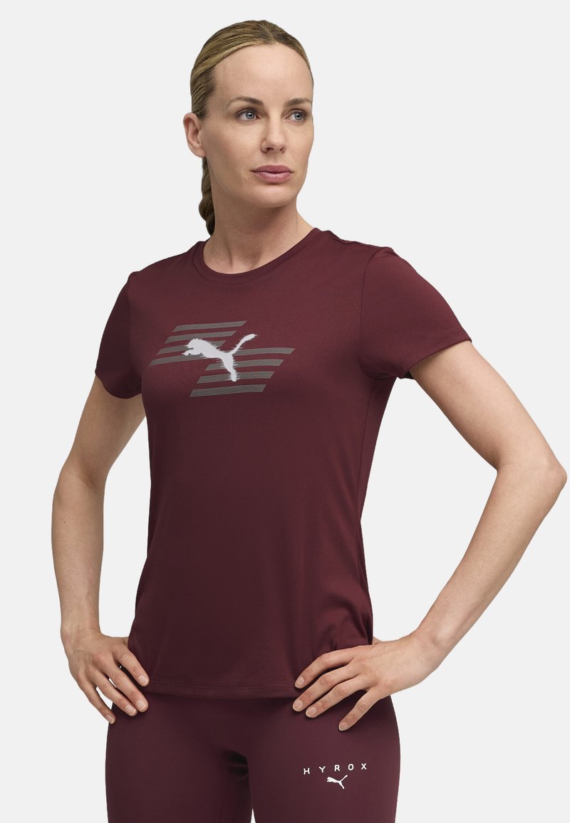 Bordo atletska majica od mekog materijala, s bijelim Puma logotipom i prugastim dizajnom na prednjoj strani. Kratki rukavi, okrugli izrez.
