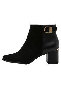 Botines negros de tobillo que combinan ante y cuero, con punta puntiaguda, tacón ancho de altura media y un detalle de hebilla dorada.