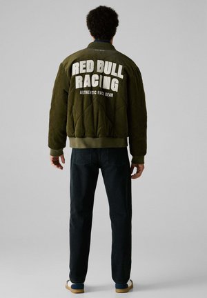 Grøn quiltet bomberjakke med "RED BULL RACING" og "AUTHENTIC RACE GEAR" trykt i hvidt på ryggen, ribbede manchetter og kant.