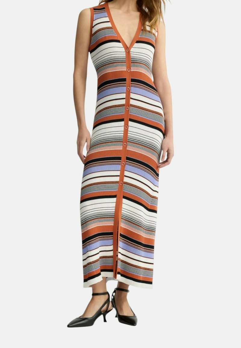 Femme portant une robe sans manches mi-mollet avec des boutons verticaux et des rayures horizontales orange, noir, blanc, violet et beige, associée à des talons noirs.