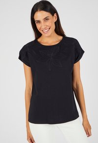Zwarte katoenen T-shirt met geborduurde bloemenontwerpen op de schouders, ronde halslijn en korte mouwen. Soepele textuur en een ontspannen pasvorm.