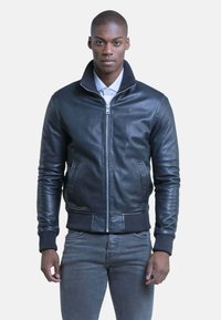 Zwarte leren bomberjack met een staande kraag, ritssluiting aan de voorkant, ribgebreide manchetten en zoom, en twee zijzakken. Glad textuur.