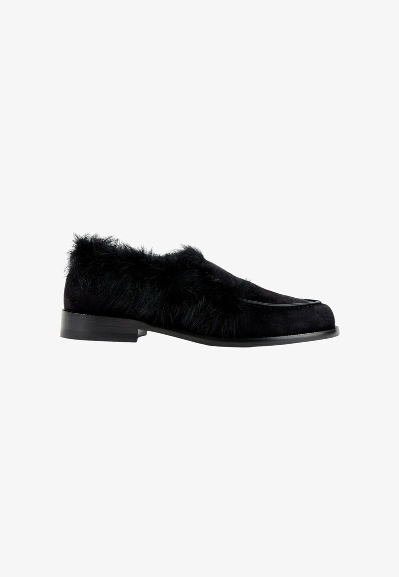 Chaussure loafer noire avec une semelle plate et une fourrure duveteuse couvrant les côtés supérieurs et la zone du talon.