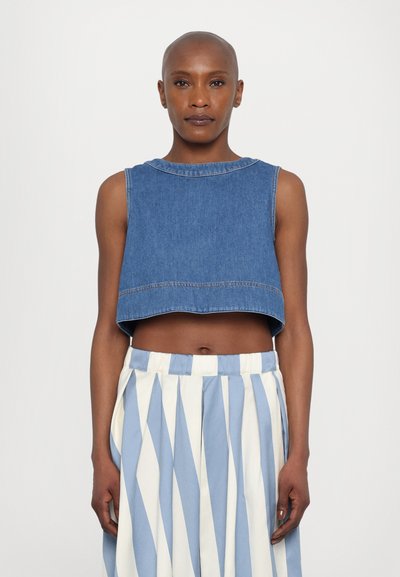 Afskåret denimtop i mellemblå med rund hals og ærmeløs design. Sammen med en stribet nederdel i blå og hvid.