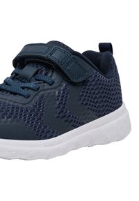 Sneaker in rete blu con finitura texture, dotata di una fascia in velcro, suola in gomma bianca a contrasto e dettagli in rilievo sul lato.