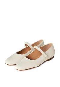 Bailarinas de cuero blanco con puntera cuadrada y una correa sobre el empeine. Textura suave, tacón bajo y plantilla marrón. Diseño simple y elegante.