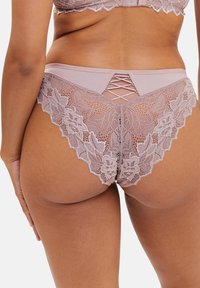 Sous-vêtements en dentelle de couleur mauve doux, avec un bord en dentelle festonné et un détail croisé à l'arrière, alliant textures et éléments de design.