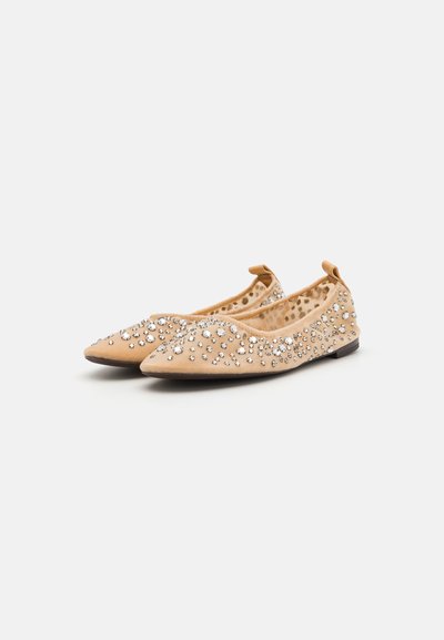 Ballerines nues à bout pointu, décorées de strass argentés. Partie supérieure en tissu doux avec une semelle plate et une languette à l'arrière pour un enfilage facile.